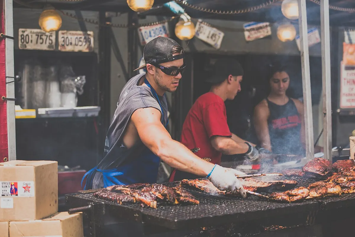 Parrillero volteando costillas sobre el carbón