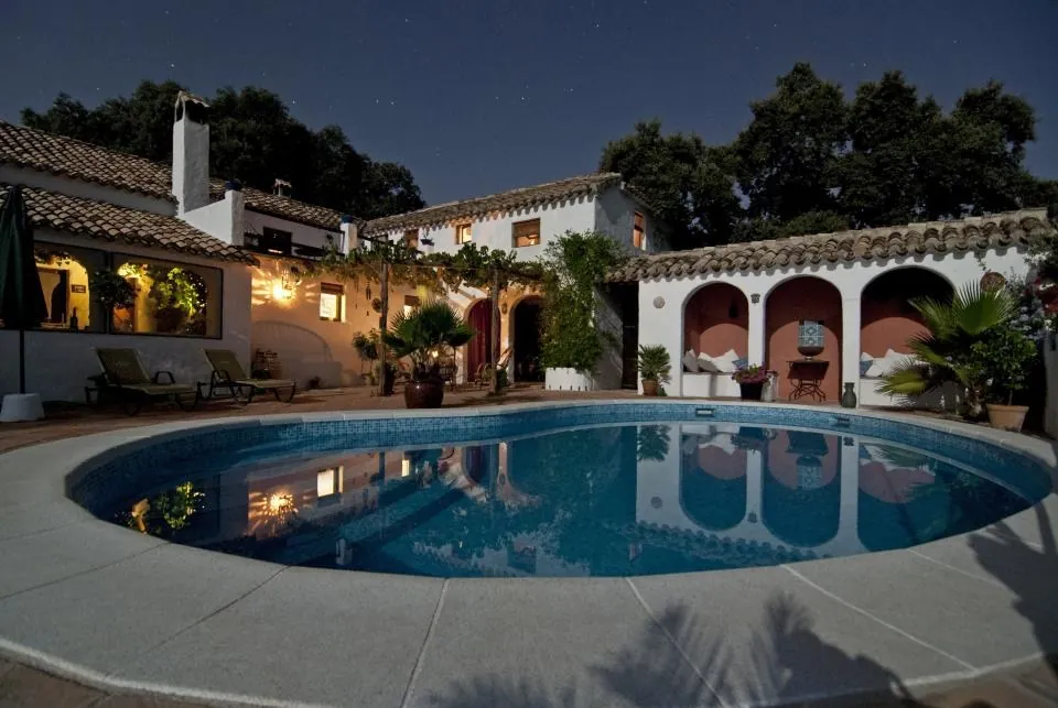 Casa principal con piscina iluminada al anochecer